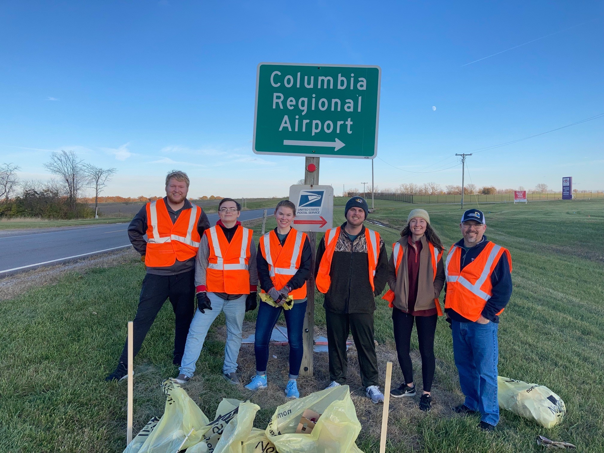 Students and faculty member with trash bags along Highway H