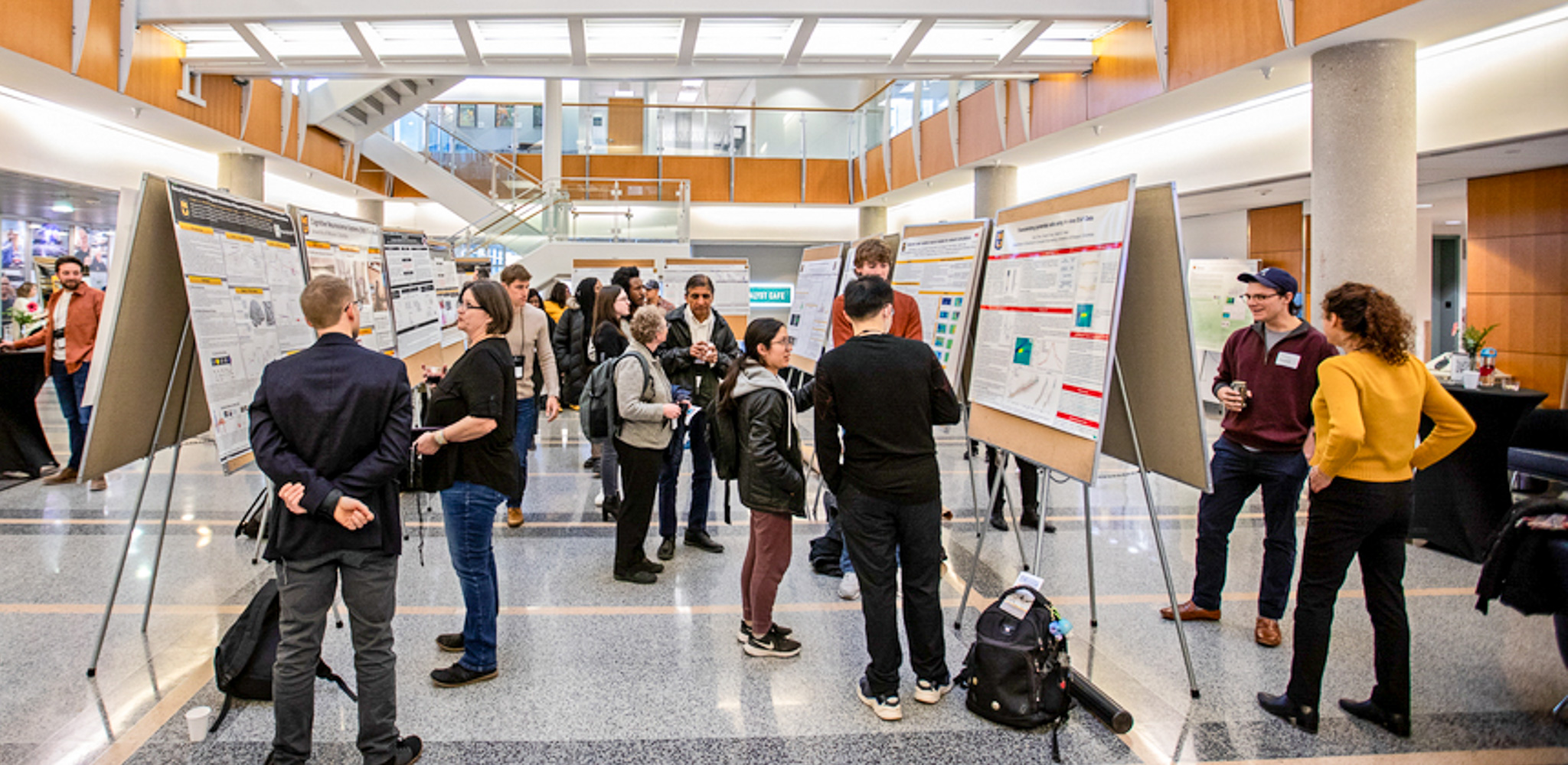 A photo of faculty, staff, and students presenting posters and discussions at a symposium