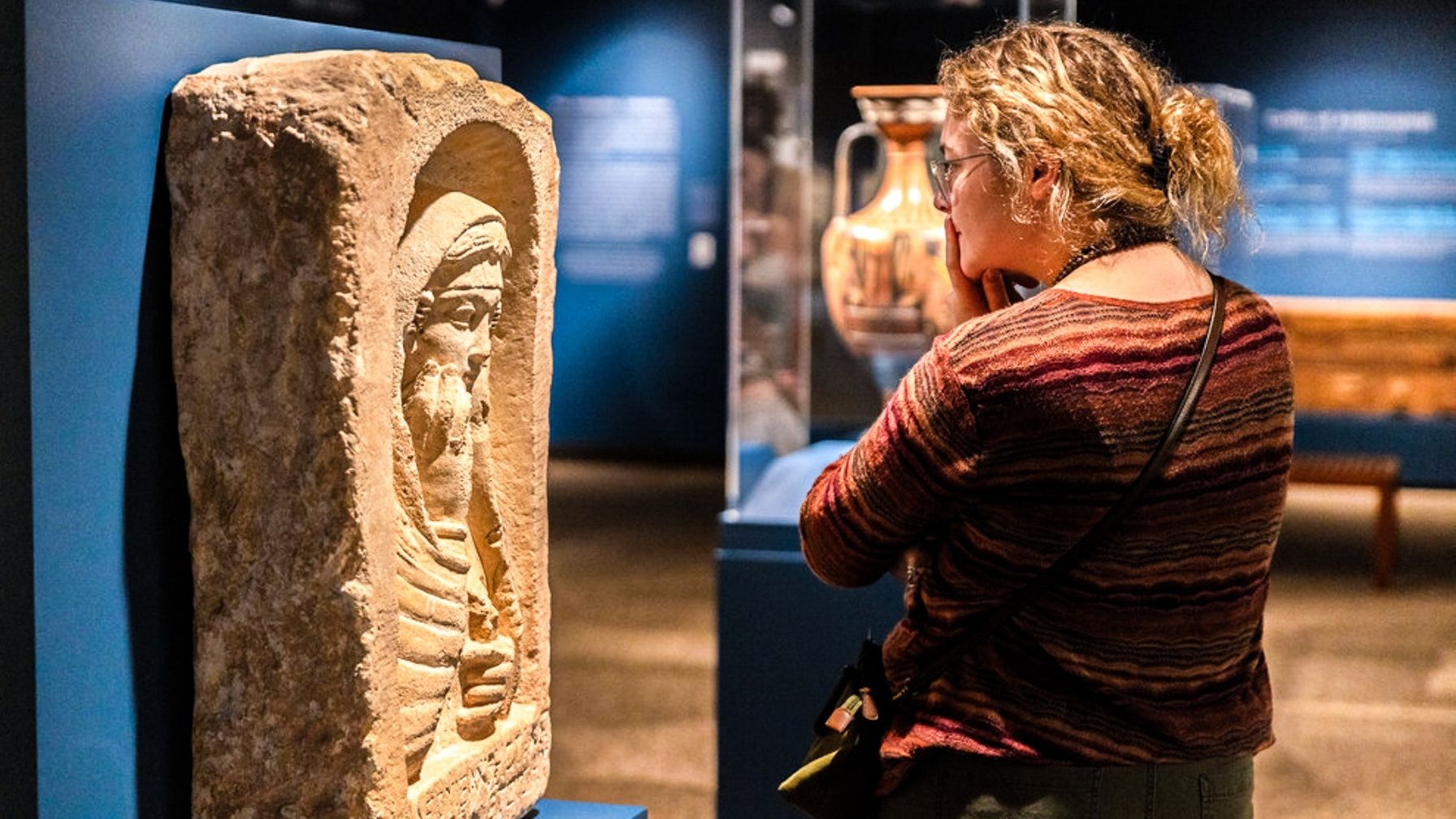 A photo of a lady looking at a stone like figure with intrigue