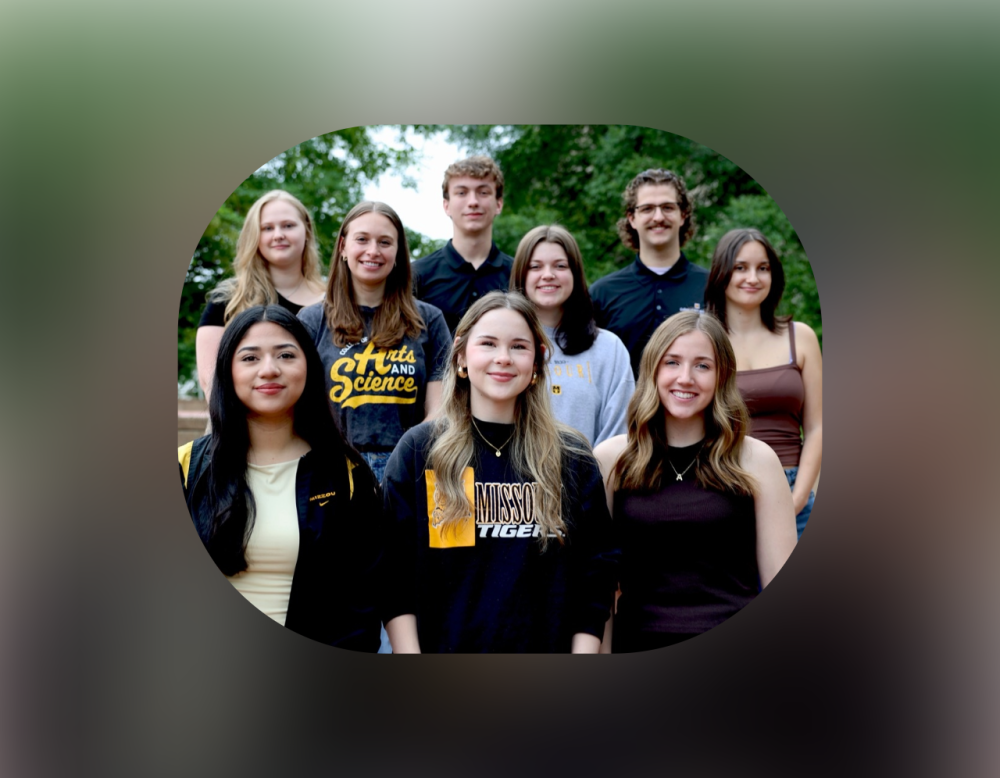 Group of nine students posing outdoors in front of green trees, several wearing University of Missouri apparel and school spirit clothing.