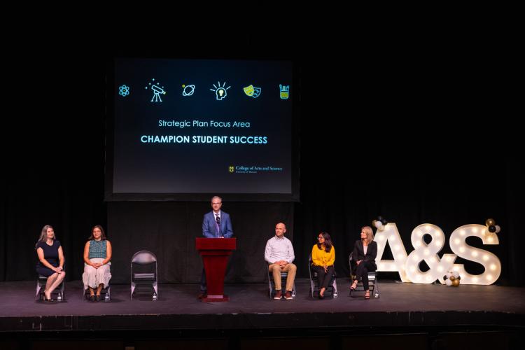 speakers on stage in front of presentation screen