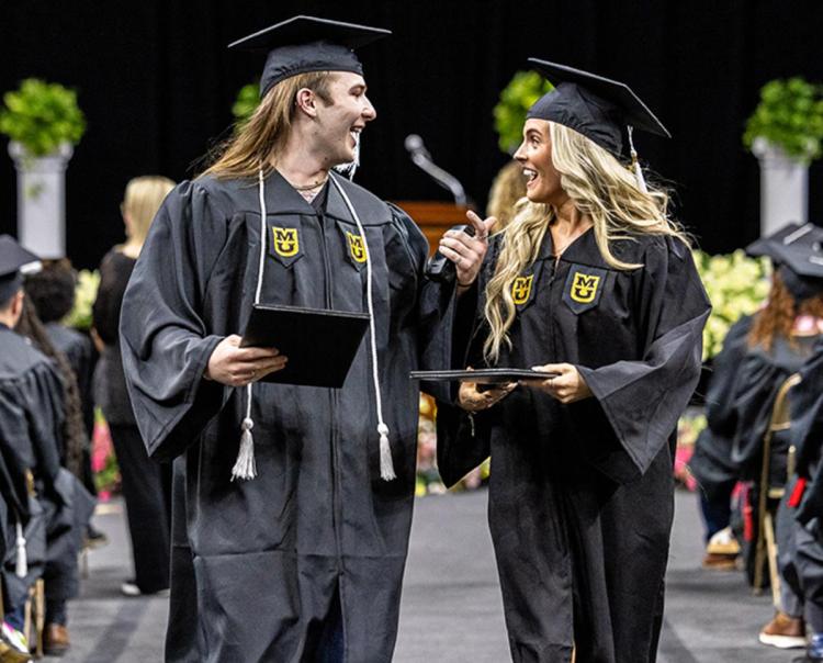 Two students looking at each other who are excited about having graduated