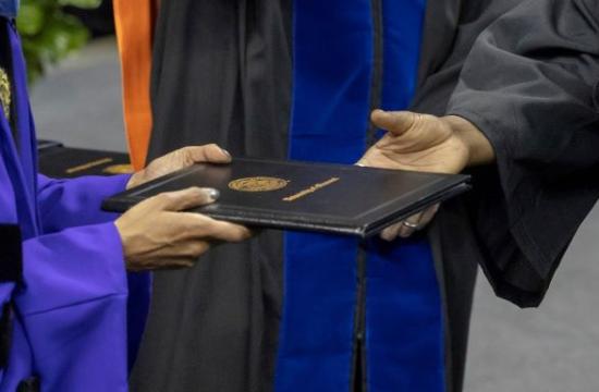photo of degree cover being handed to graduating student
