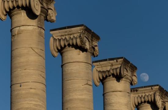 The top of the columns, the sky is blue, and you can see the moon above the column